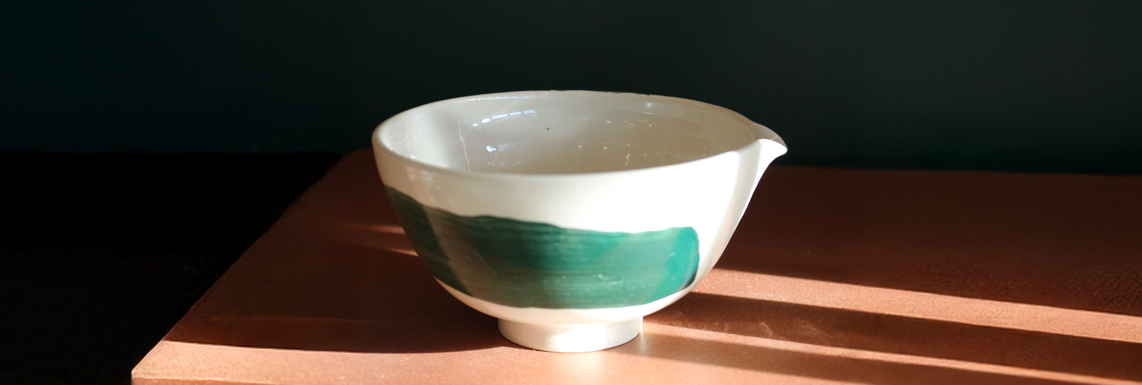 Ceramic bowl with green accent on a wooden surface